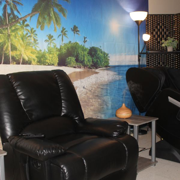  room with black massage chairs and beach wall mural